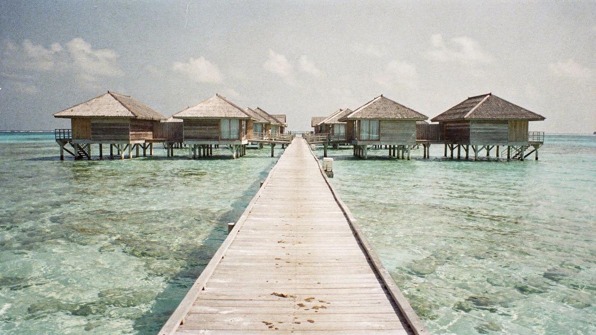 Overwater villas on a Maldivian atoll seen from the jetty at midday